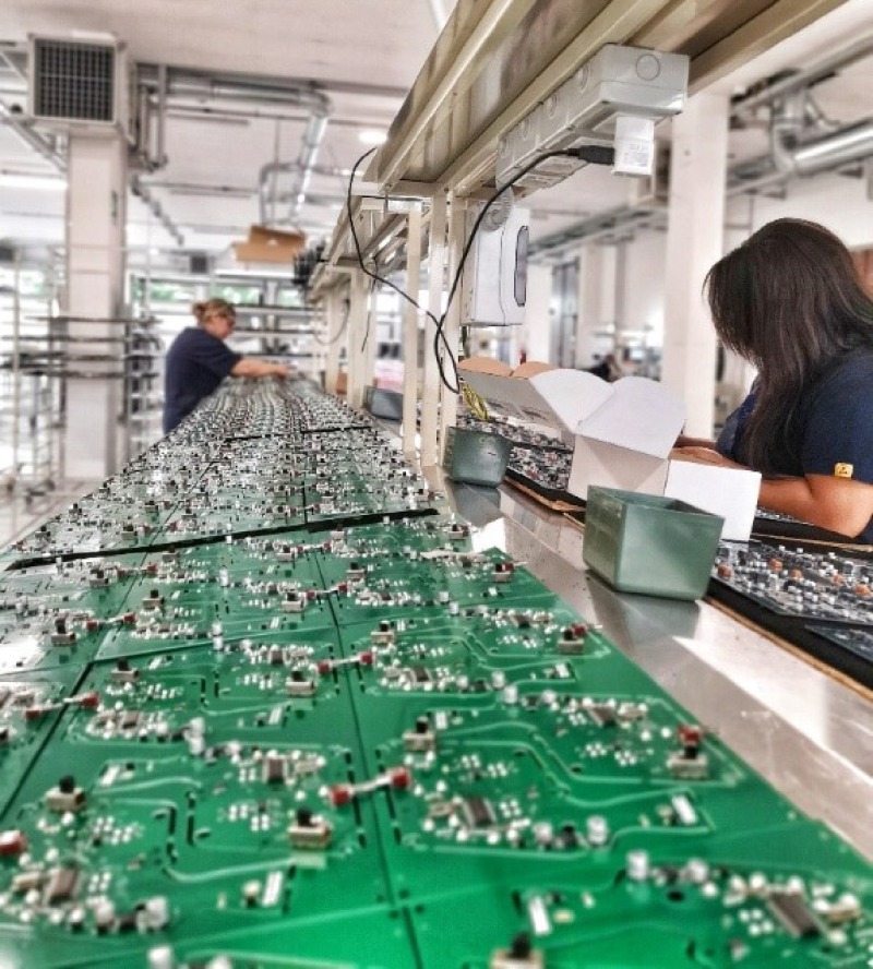 Los operadores ensamblan a mano los componentes en la placa electrónica.